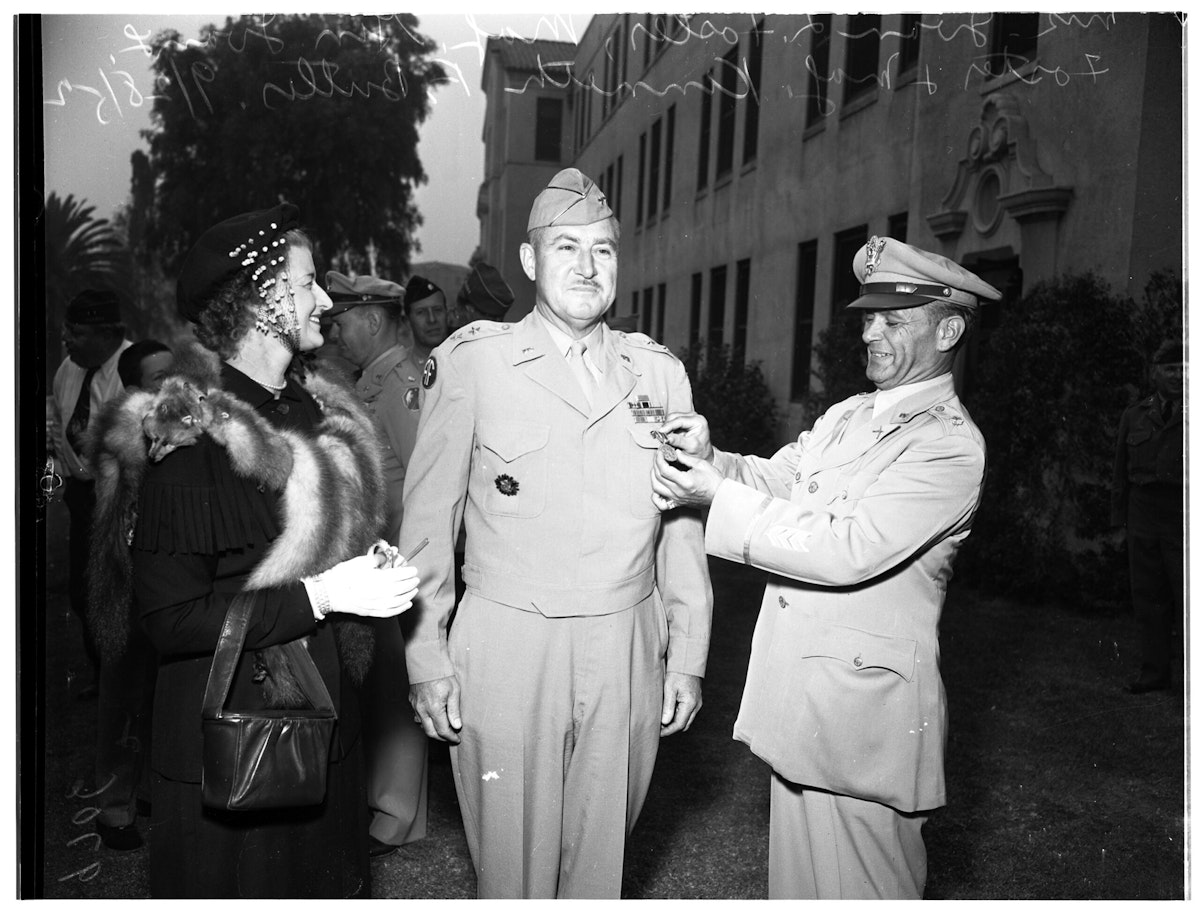 Major Kenneth F Butler pins a Veterans of Foreign Wars citizenship medal on Major General Ivan L Foster.