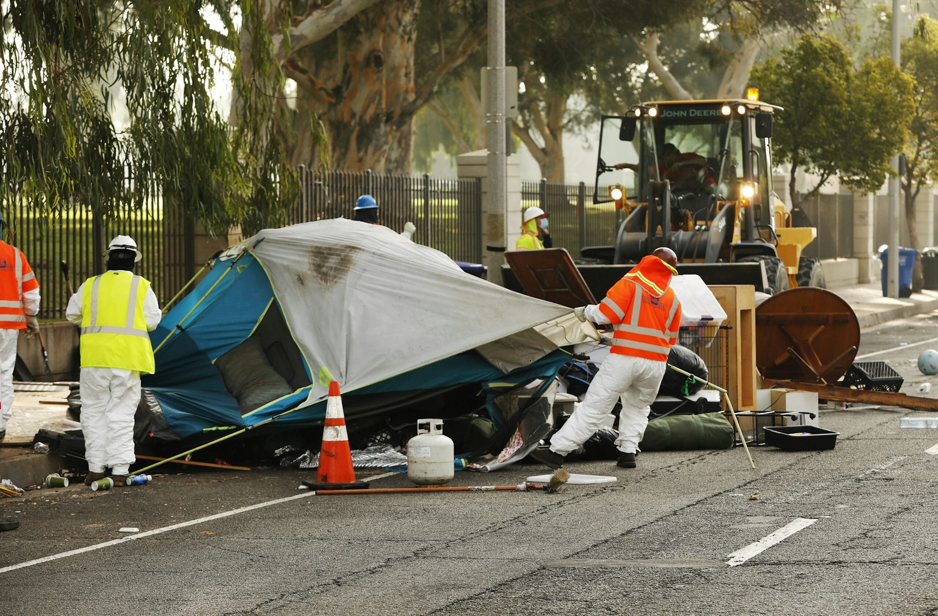 Clean-up workers in hazmat suits dismantle tents and homeless encampments outside the West LA VA.
