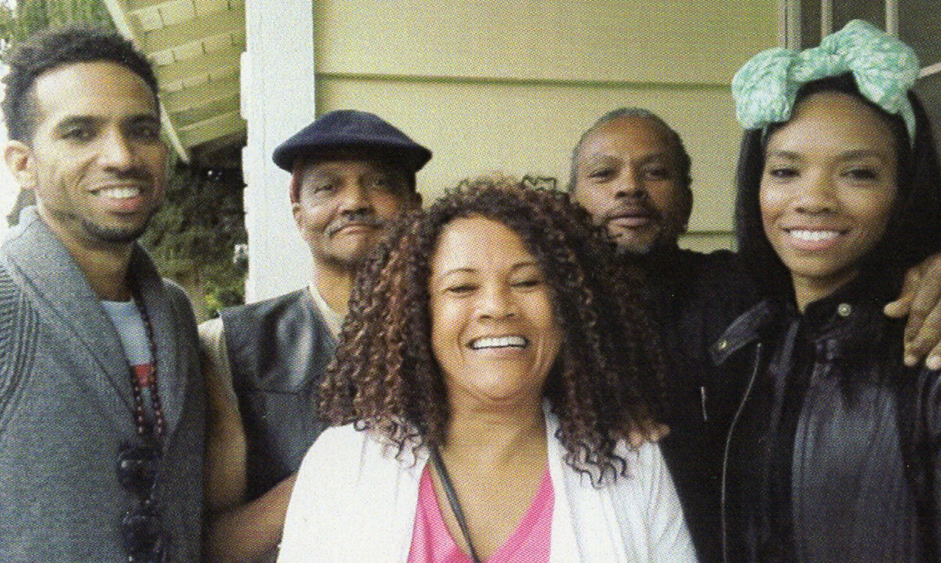 Andre Butler, wearing a hat, poses with two men and two women, all smiling.