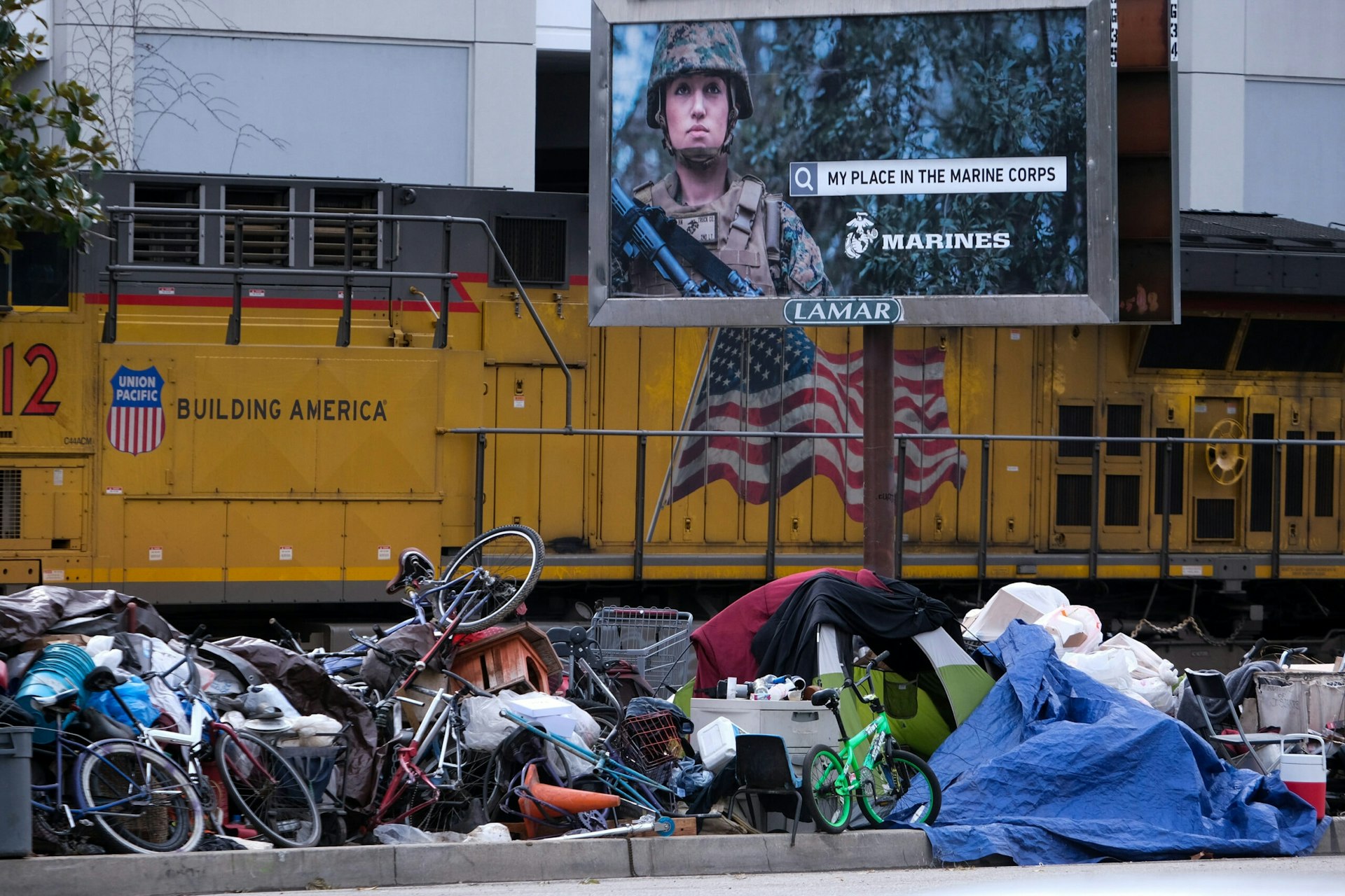 A Marine Corps billboard stands over a homeless encampment in Los Angeles.