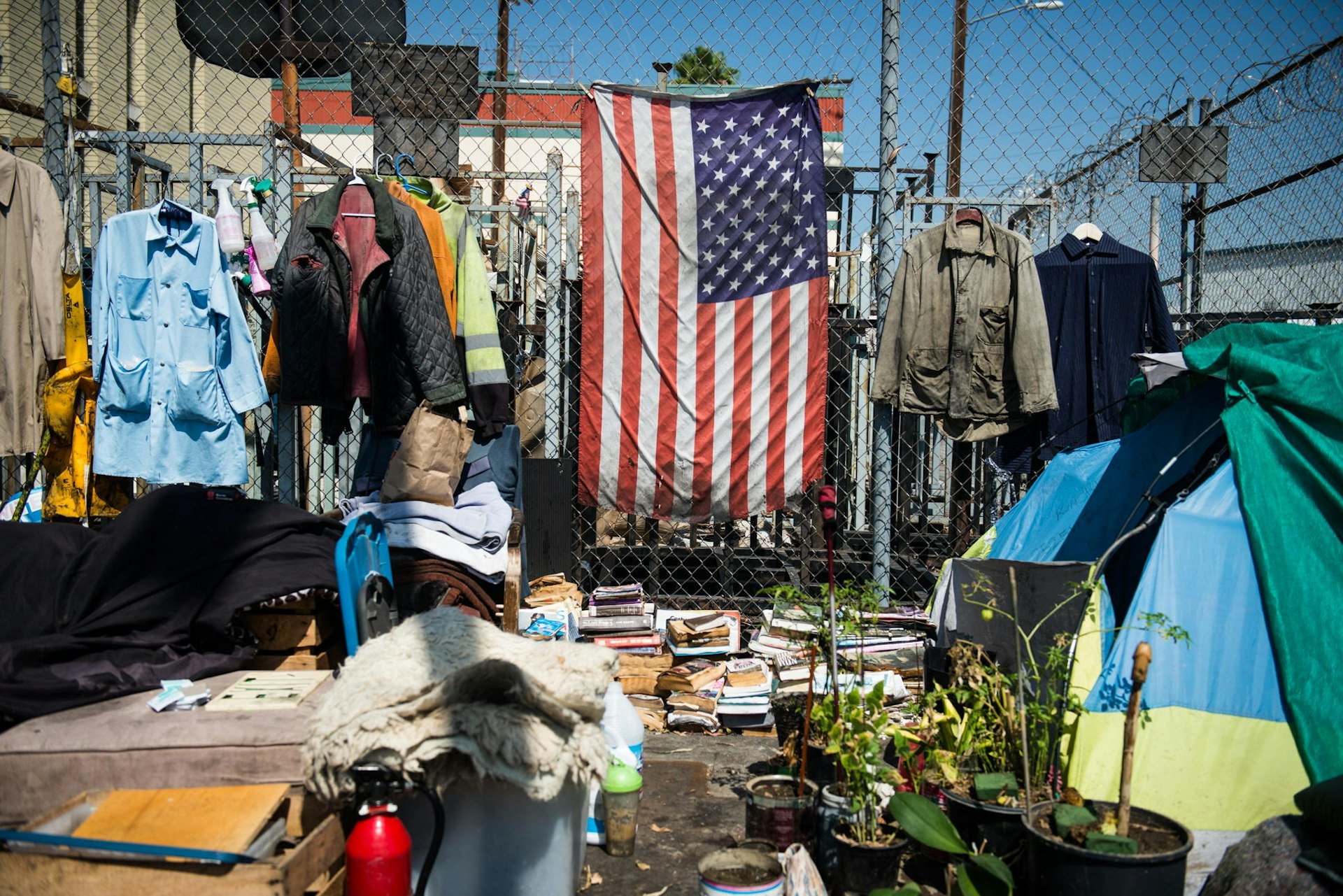 An American flag hangs in Skid Row, surrounded by clothing, books, tents and personal belongings in a homeless encampment.