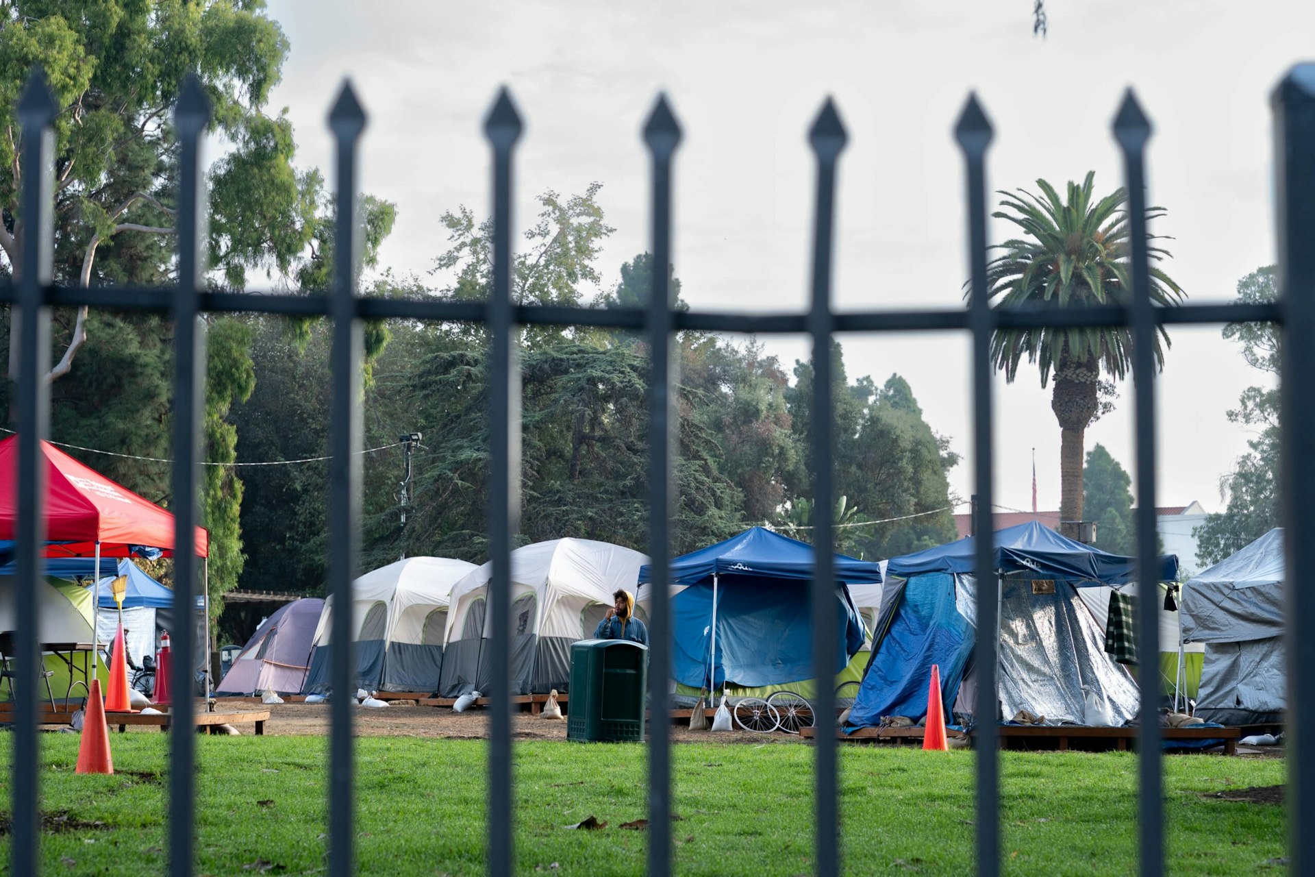 Several homeless encampment tents are seen through the fence of the VA facility in Los Angeles.