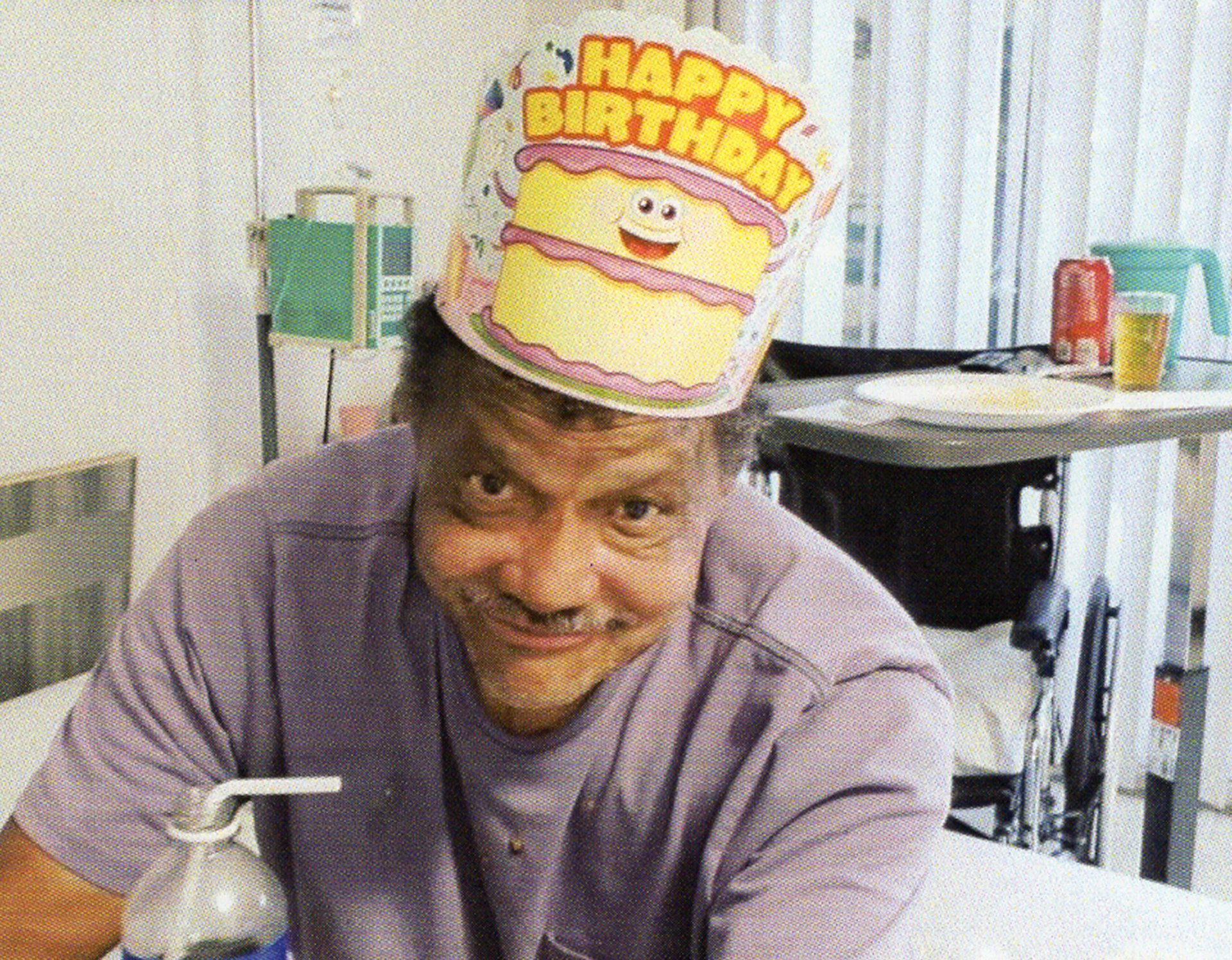 Andre Butler smiles wearing a "Happy Birthday" hat, in a hospital room.