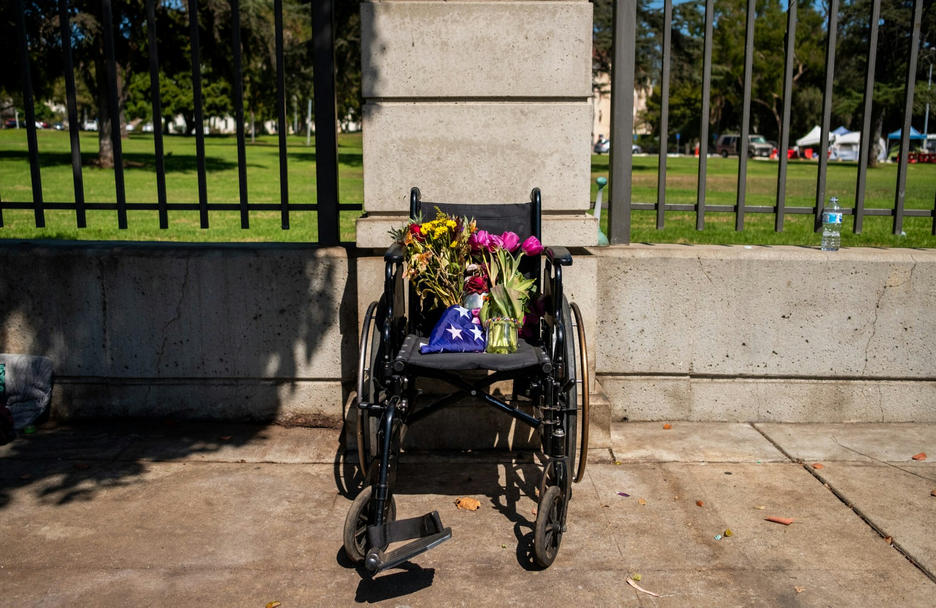 Flowers are left on a wheelchair outside the gates of the West LA VA.