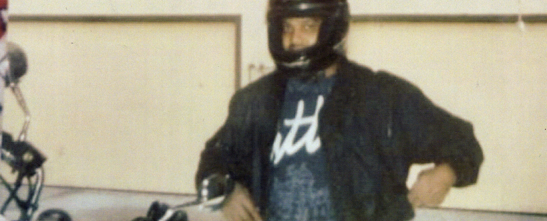Andre Butler poses next to a motorcycle, wearing a helmet.