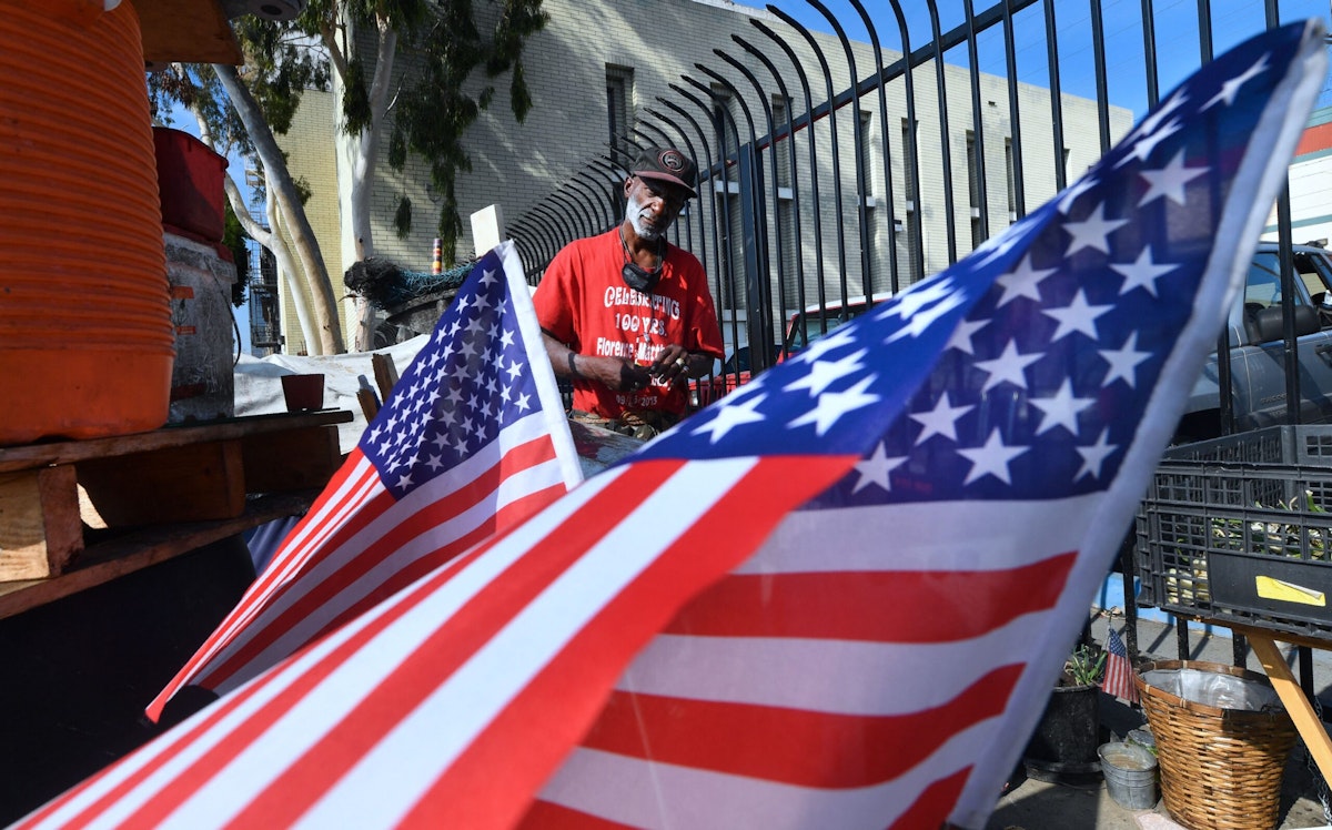 Flags at the street-corner encampment of a homeless veteran.